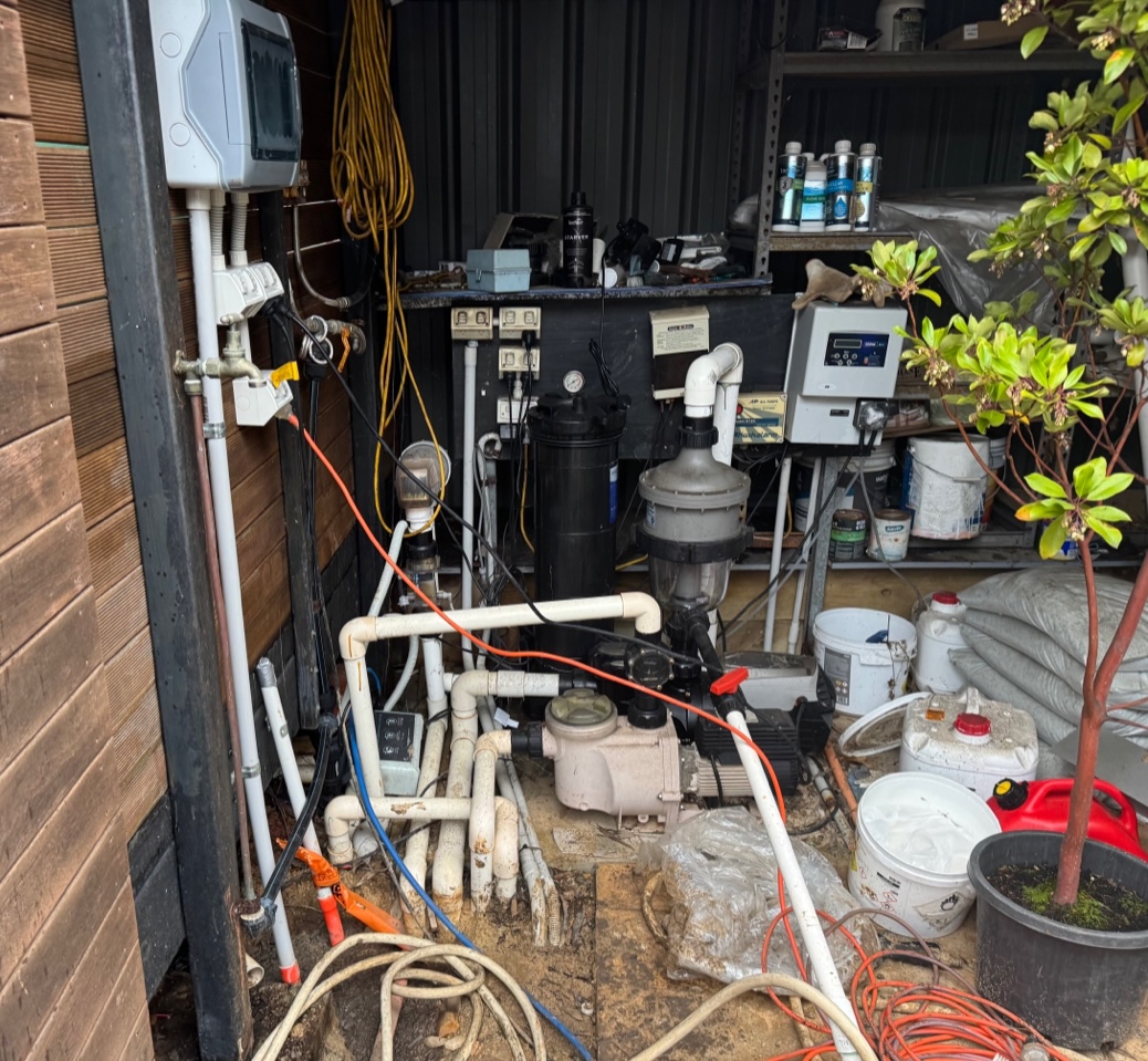 Traditional pool plant room with exposed pumps, pipes, filters and wiring