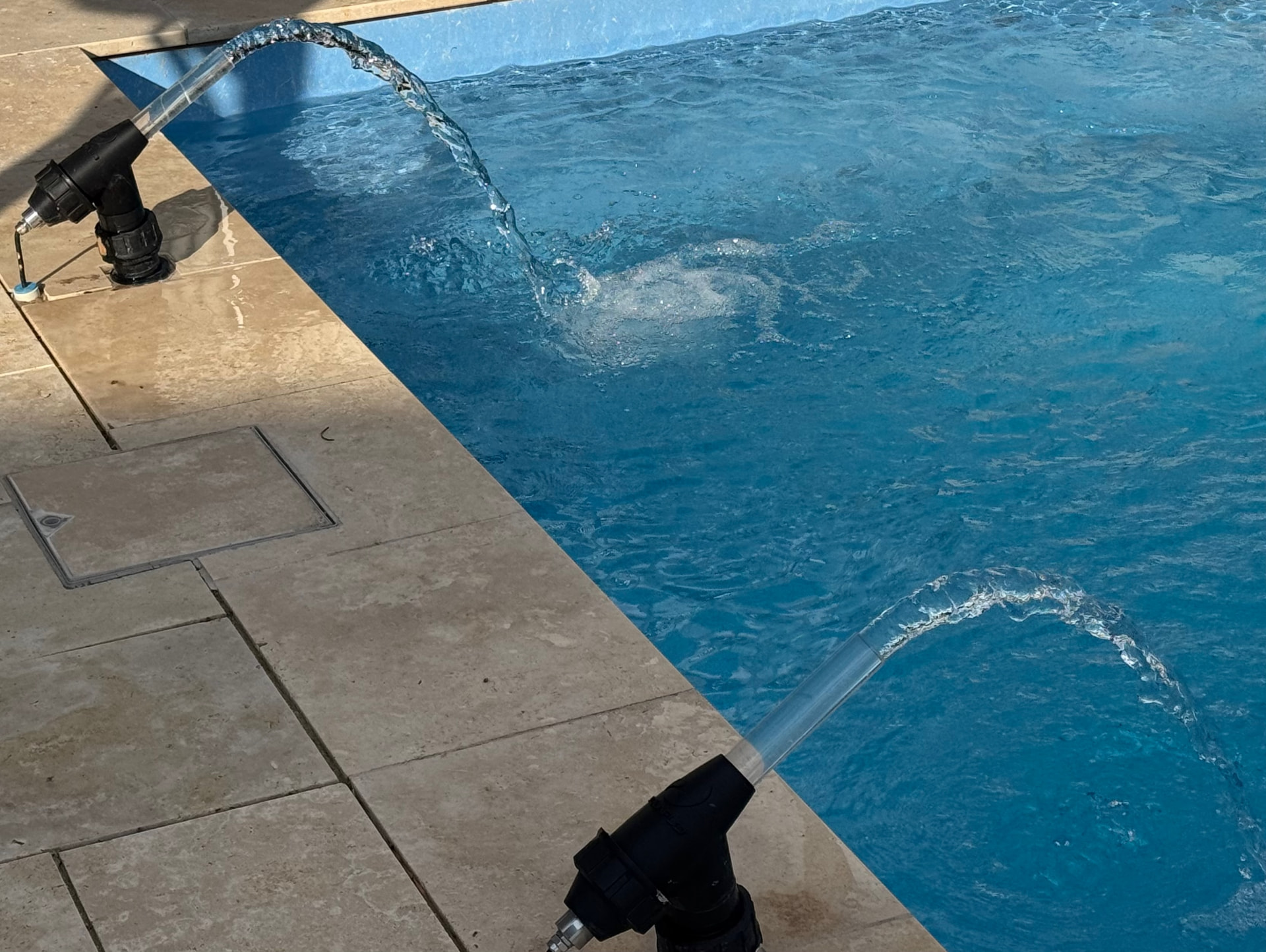 Two laminar jets arcing clear ribbons of water into a pool