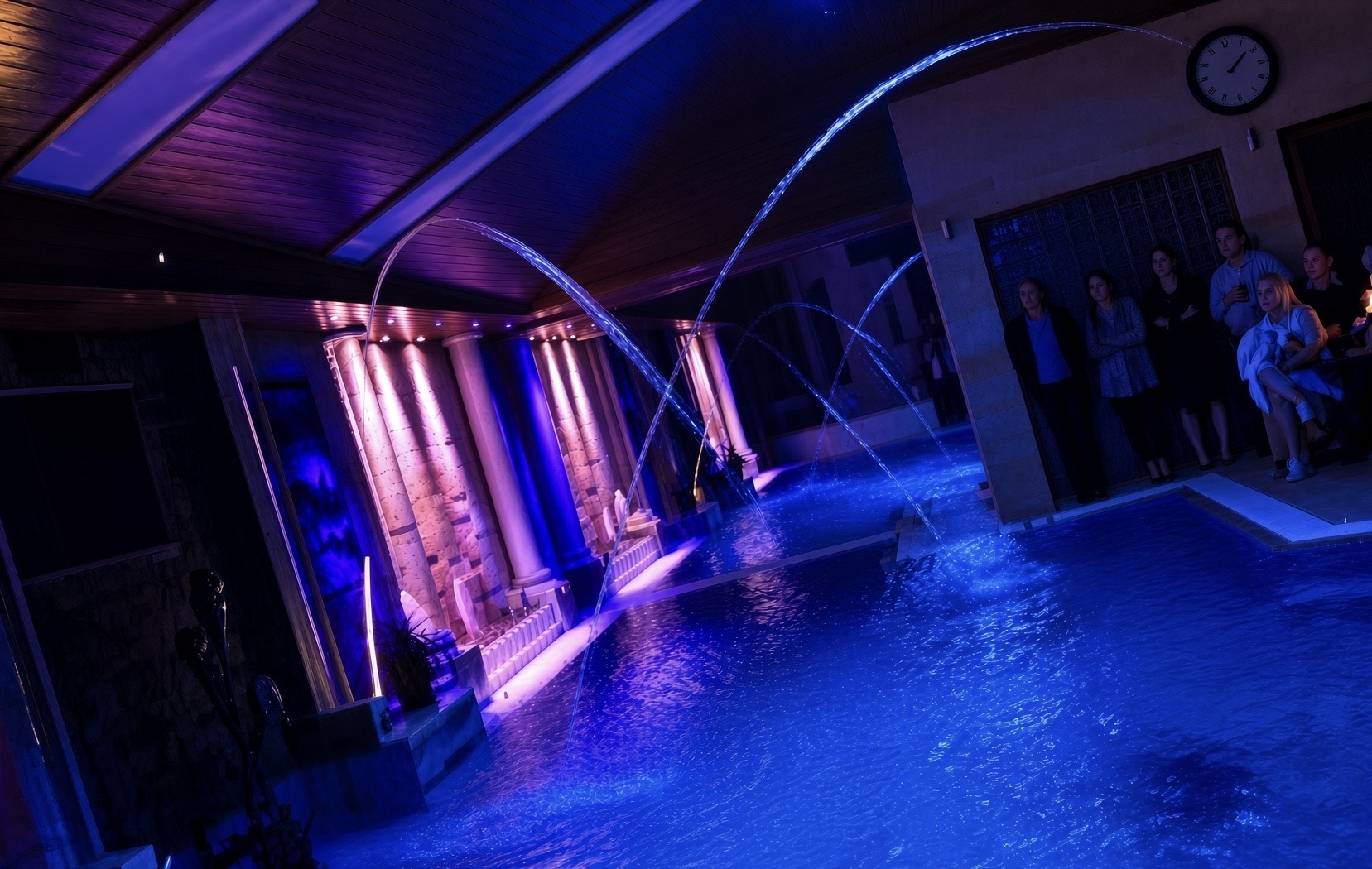 Indoor pool with illuminated laminar water arcs