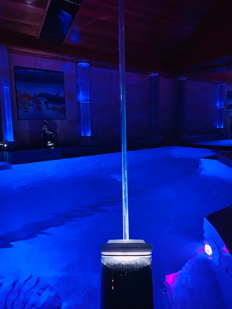 Vertical laminar water column rising from a lit pool